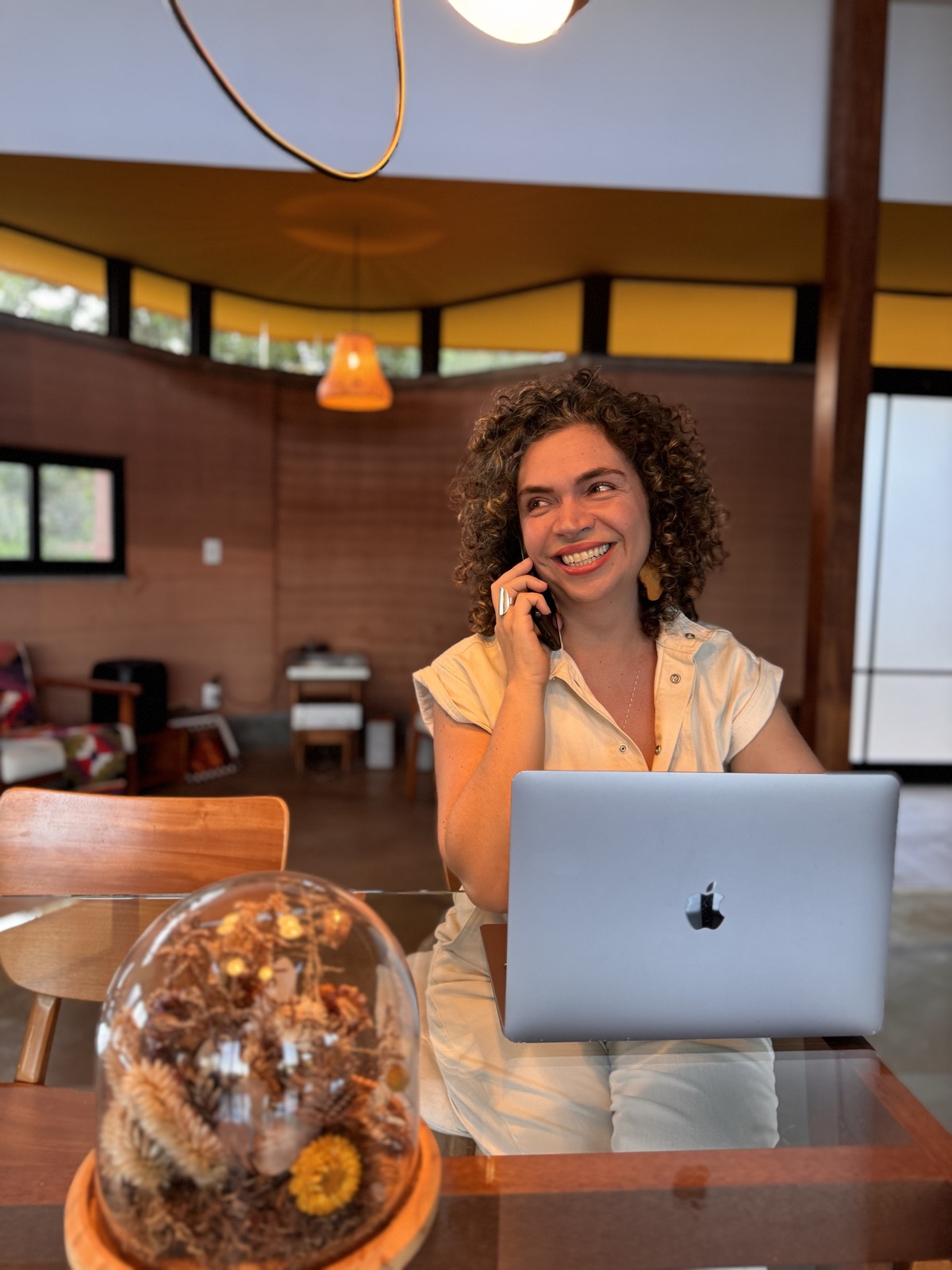 Rita Monte sorrindo ao telefone, com o computador e o celular